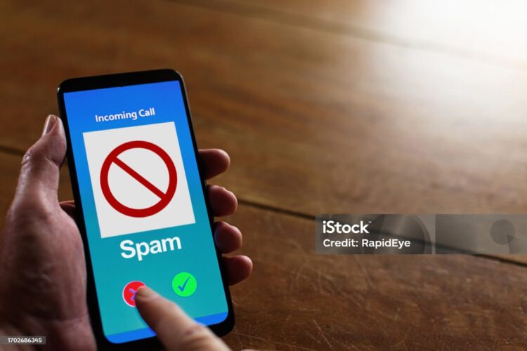 Man's finger presses the red button on a call that his cellphone has flagged as spam. The phone interface is simulated by the photographer, so there are no copyright issues.
